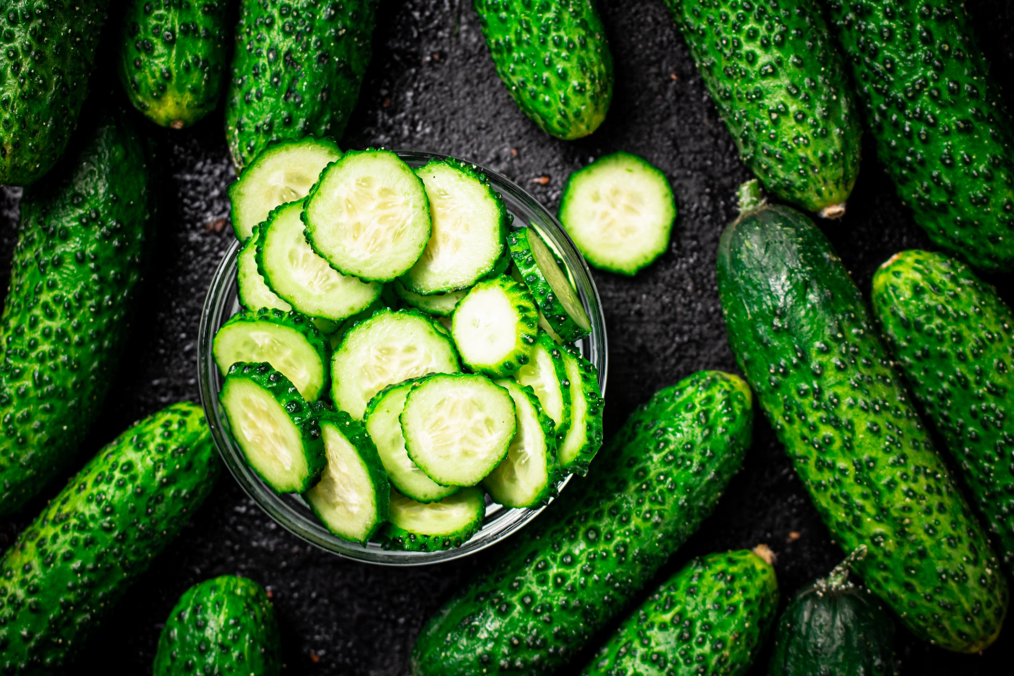 Sliced and whole cucumbers on the table.